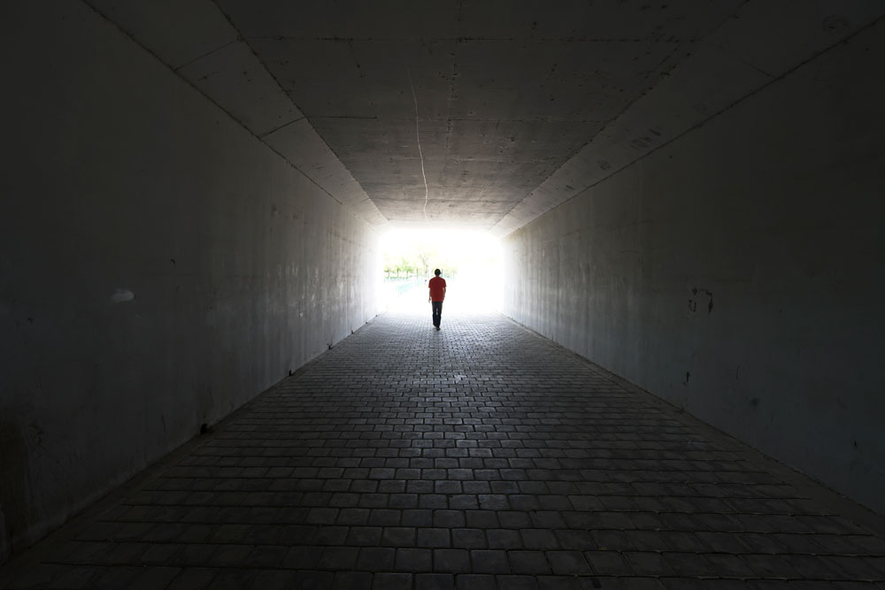 En person går i en mörk tunnel